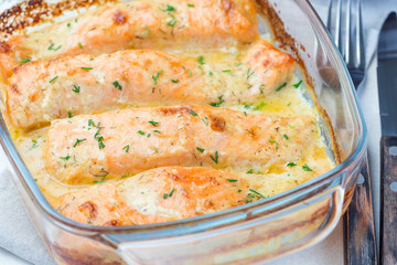 Baked in creamy sauce salmon in a glass baking dish, horizontal