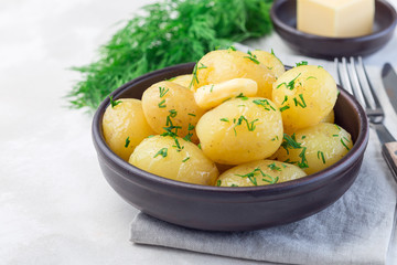 Naklejka na ściany i meble New young boiled potato topped with melted butter and chopped dill in ceramic bowl, horizontal, copy space