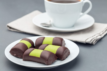 Swedish sweets punsch rolls or punschrullar, covered with green marzipan, on  white plate, served with coffee,  horizontal
