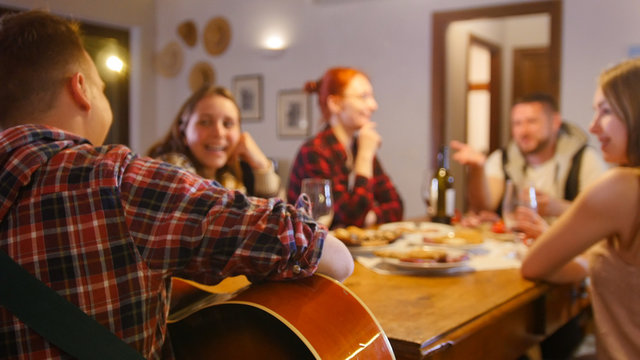 Friends having a party - drinking and singing songs by the guitar