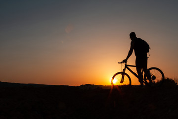 Naklejka na ściany i meble Man with mountain bike at sunrise