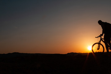 Obraz premium Man with mountain bike at sunrise