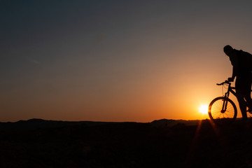 Obraz premium Man with mountain bike at sunrise