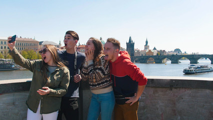 Company of friends stand on the bridge and take a selfie in the Czech, Prague