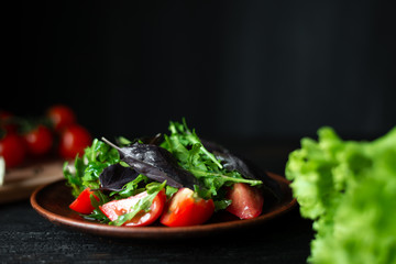 view from the side on a wooden plate lined with salad from fresh juicy vegetables with fresh greens