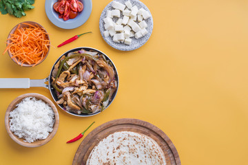 Fajitas and ingredients top view and yellow background
