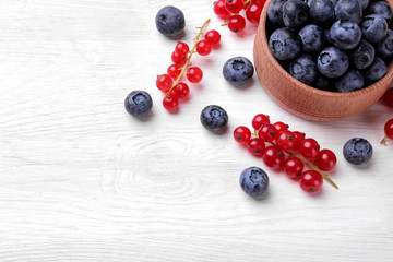 Tasty blueberry berries in a bowl on a white wooden table. place for text. top view