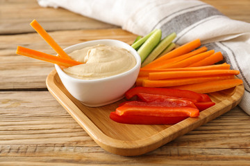 Bowl of tasty sauce and fresh vegetables on wooden table