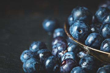 Juicy and fresh blueberries with green leaves on rustic table. Blueberry antioxidant. Concept for healthy eating and nutrition. Selective focus.