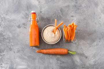 Bowl of tasty sauce and fresh carrot with juice on grunge background