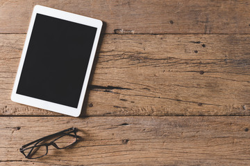 Top view of Pen, notebook, glasses, tablet on wooden table and copy space