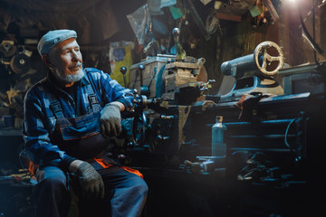Fototapeta na wymiar Senior elderly male turner handles metal on machine. Concept pension worker industrial, workplace