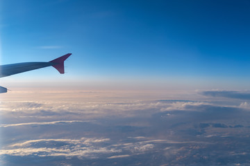 Up in the air, view of aircraft wing silhouette with dark blue sky horizon and cloud background in...