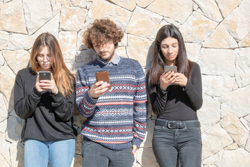 Groupe de jeunes multiracial, s'ignorant les uns les autres, sur leur smartphone