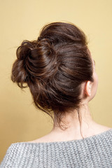 Rear view of female hairstyle medium bun on long straight brown hair with radical volume