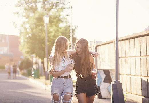 Two girls best friends in summer hipster clothes posing on the street background. 