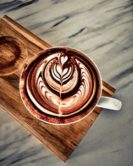 cup of coffee latte on dark wood table, beautiful latte art.