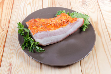 Pice of boiled smoked pork belly on dish with greens