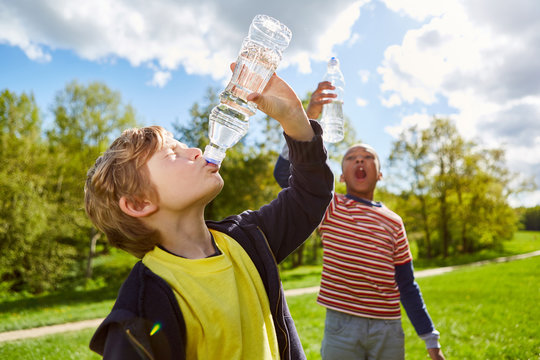 Zwei Kinder trinken durstig aus Wasserflaschen