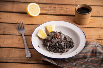 Plate of black rice with squid and prawns or Valencian black paella