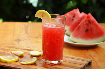 Colorful tropical fresh watermelon smoothie summer drinks in the glasses on wood table background. Refreshing watermelon coсtail with slimon of green foliage. The concept of leisure, travel