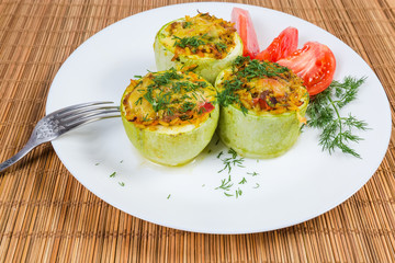 Baked stuffed pieces of vegetable marrow and fresh tomato slices