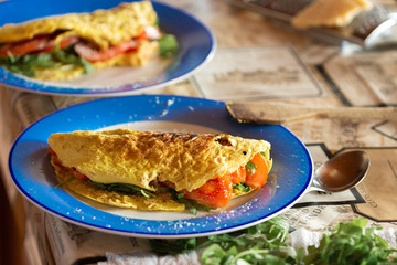 Healthy breakfast. Omelet with tomatoes and arugula on a plate in the home kitchen
