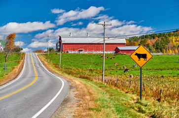 Highway and red barn at sunny autumn day in New Hampshire, USA