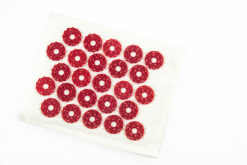 Acupuncture orthopedic massage mat with needles and spikes for feet and body isolated on white background. Alternative medicine, health care, recreation and muscle relaxation concept.