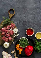Sliced beef fillet with vegetable. kitchen table with сuts meat and veggies on dark table top view. Ingredients cooking meat