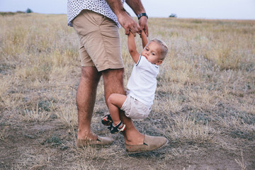 Fototapeta premium smiling toddler hugging his father and holding his leg