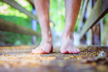 Forest adventure: Closeup of barefoot male feet on a wooden bridge in the woodland