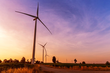 Fototapeta na wymiar Wind turbines electric power generator on sunset sky at agriculture field