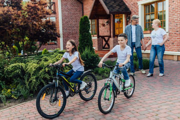 Obraz premium Happy aged couple meeting kids and walking with they on garden.