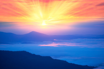 Obrazy na Szkle  Mgliste chmury w górach o wschodzie słońca