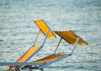 typical yellow or orange sunbeds of the Riviera Romagnola adriatic coast of Italy, with the sea in the background. Rimini Beach