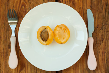 Ripe fresh apricot fruits on a white plate on the wooden background. Copy space, delisious healthy food.