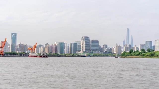 Time lapse of ships on Huangpu river.  Boats timelapse moving along turning point in waterway in Shanghai with cityscape background. Downtown cargo ships moving downstream.