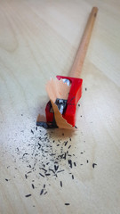 Pencil and sharpener, isolated on wood background.