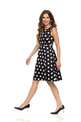 Smiling Beautiful Young Woman In Black Dotted Cocktail Dress And High Heels Is Walking And Lokking At Camera