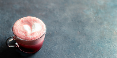 Trendy drink: pink red velvet latte. Beetroot cappuccino or latte in glass cup on black background....