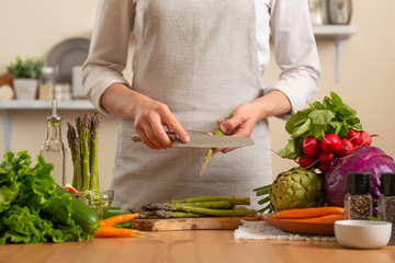 The chef cleans and cuts asparagus, with vegetables on a light background. The concept is loss of healthy and healthy food, detox, vegan food. Slow food, comfort food, clean food