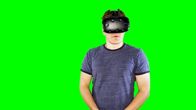 Man stops playing and takes off VR helmet. Playing virtual reality on green screen. Person looking at game world enjoying futuristic virtual entertainment at home.  Fun modern video games.