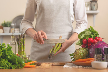 The chef cleans and cuts asparagus, with vegetables on a light background. The concept is loss of healthy and healthy food, detox, vegan food. Slow food, comfort food, clean food