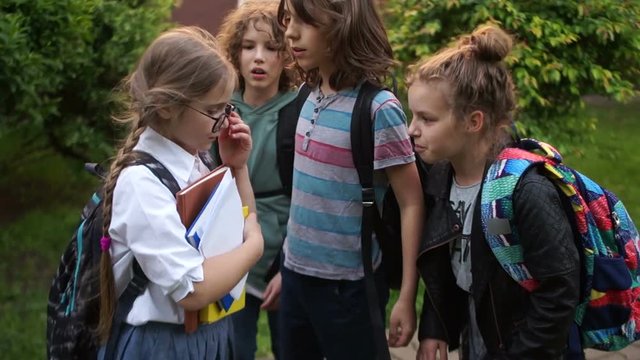 Two boys and a girl, a group of teenagers are pushing and insulting a schoolgirl. Adolescent violence problem. Bullying among adolescents and schoolchildren. Physical violence