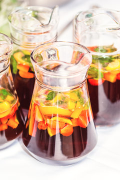 Several pither jugs with traditional British summer Pimms cocktail punch with lemonade, strawberries, cucumber, orange and mint isolated. Garden party refreshment or catering concept with copy space