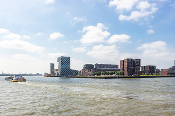 Fototapeta premium A cargo boat on the river Maas passes the building of the Netherlands Maritime University