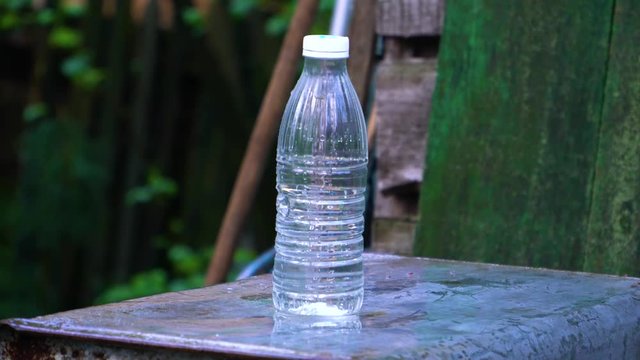 The water bottle drops sharply after being hit by a bullet.