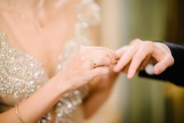 The bridegroom puts the wedding ring on the bride close up. The bride puts the bridegroom on the wedding ring.