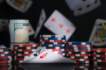 on a black background and flying cards, pyramids of chips and hundred dollar bills wrapped in a roll, for the game, on the two highest cards, aces